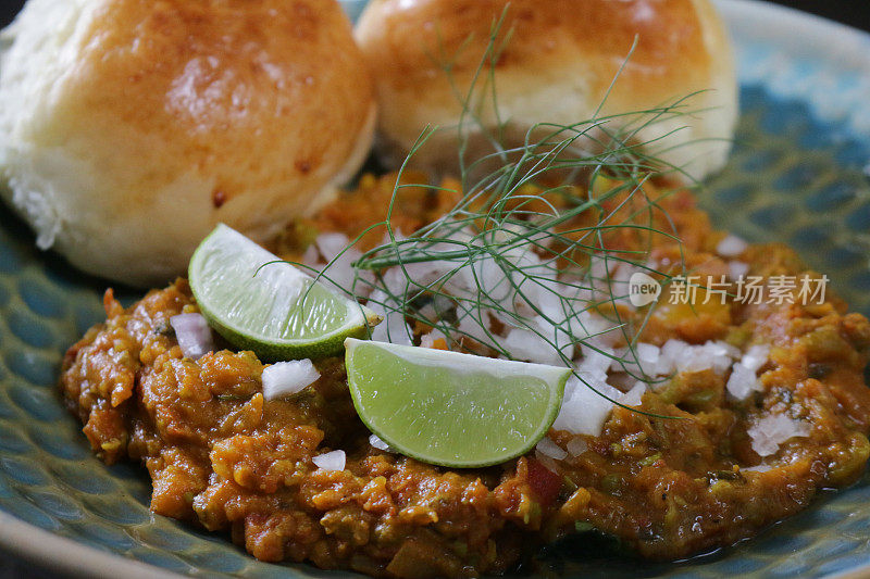 传统印度/孟买食物Pav bhaji的形象，配以新鲜出炉的面包卷，配以切碎的生洋葱和柠檬片